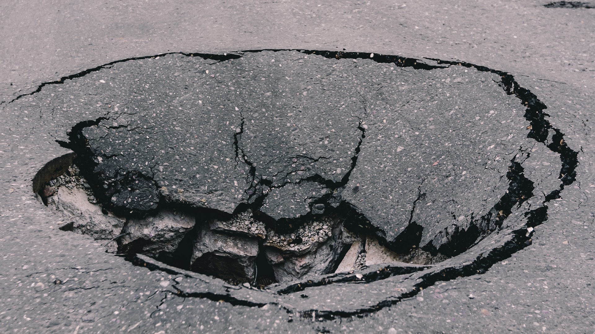 a deep sinkhole on asphalt with cracks