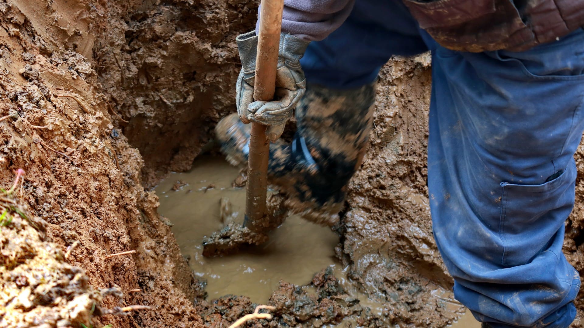 a person digs through mud with a shovel