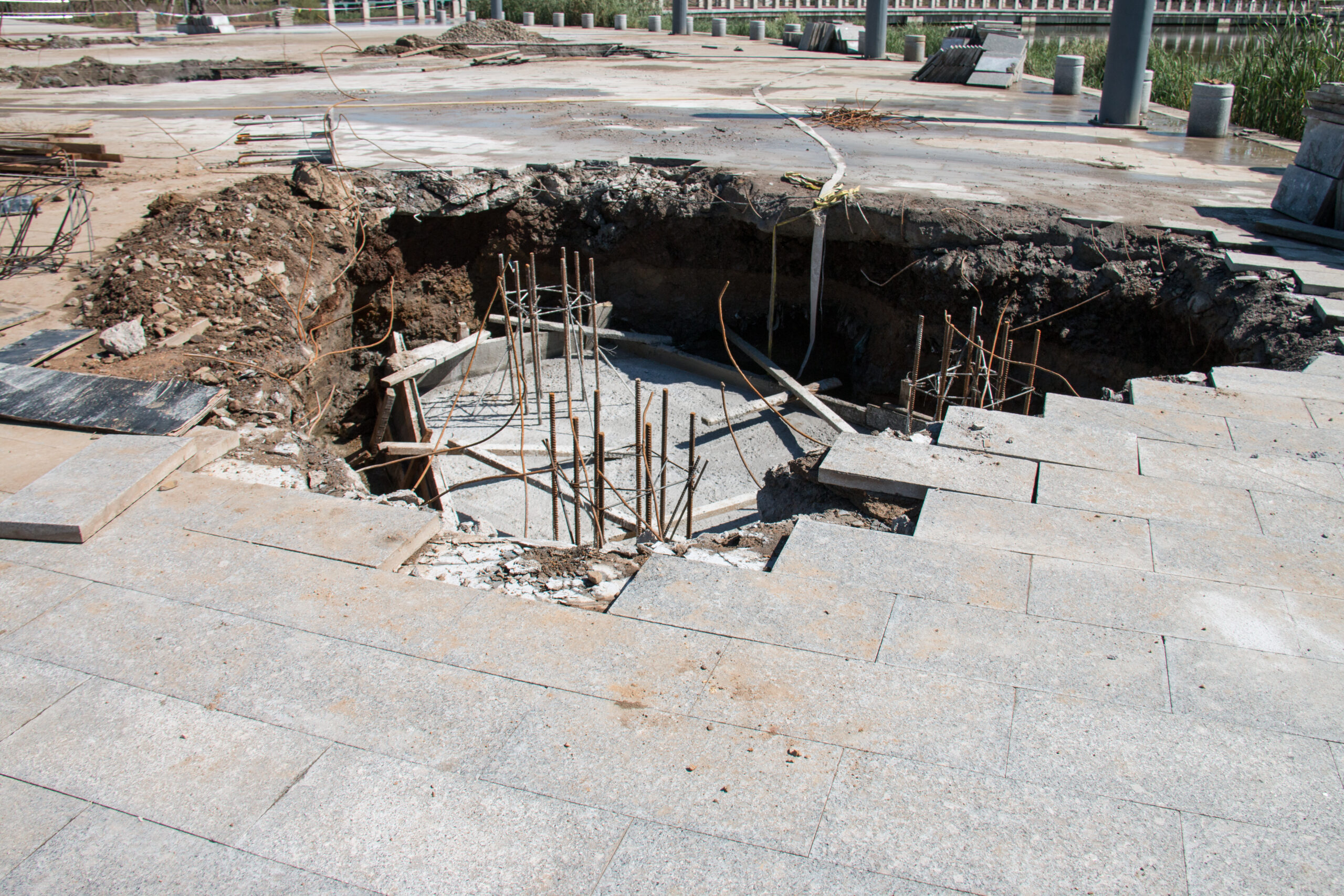 Collapsed sidewalk revealing a deep subsurface void with exposed rebar — the kind of catastrophic failure GPR void detection is designed to catch before it happens